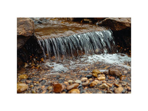 Small creek waterfall photography canvas with rocks and pebbles for peaceful bathroom wall decor.