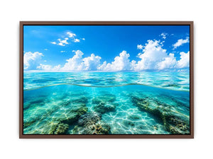 Bright split-view ocean wall art featuring crystal-clear turquoise water, underwater rock formations, and soft clouds beneath a vivid blue sky.