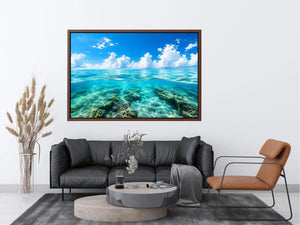 Bright split-view ocean wall art featuring crystal-clear turquoise water, underwater rock formations, and soft clouds beneath a vivid blue sky.