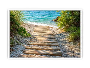 Rustic wooden pathway leading across a pebble beach toward turquoise ocean waves