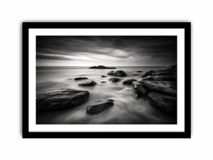Black and white ocean wall art with dramatic coastal rocks, misty waves, and moody storm clouds in contemporary monochrome seascape style