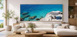 Turquoise coastal cove canvas art with white rocks, striped umbrella and clear sea.