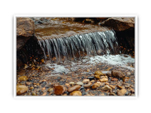 Small creek waterfall photography canvas with rocks and pebbles for peaceful bathroom wall decor.