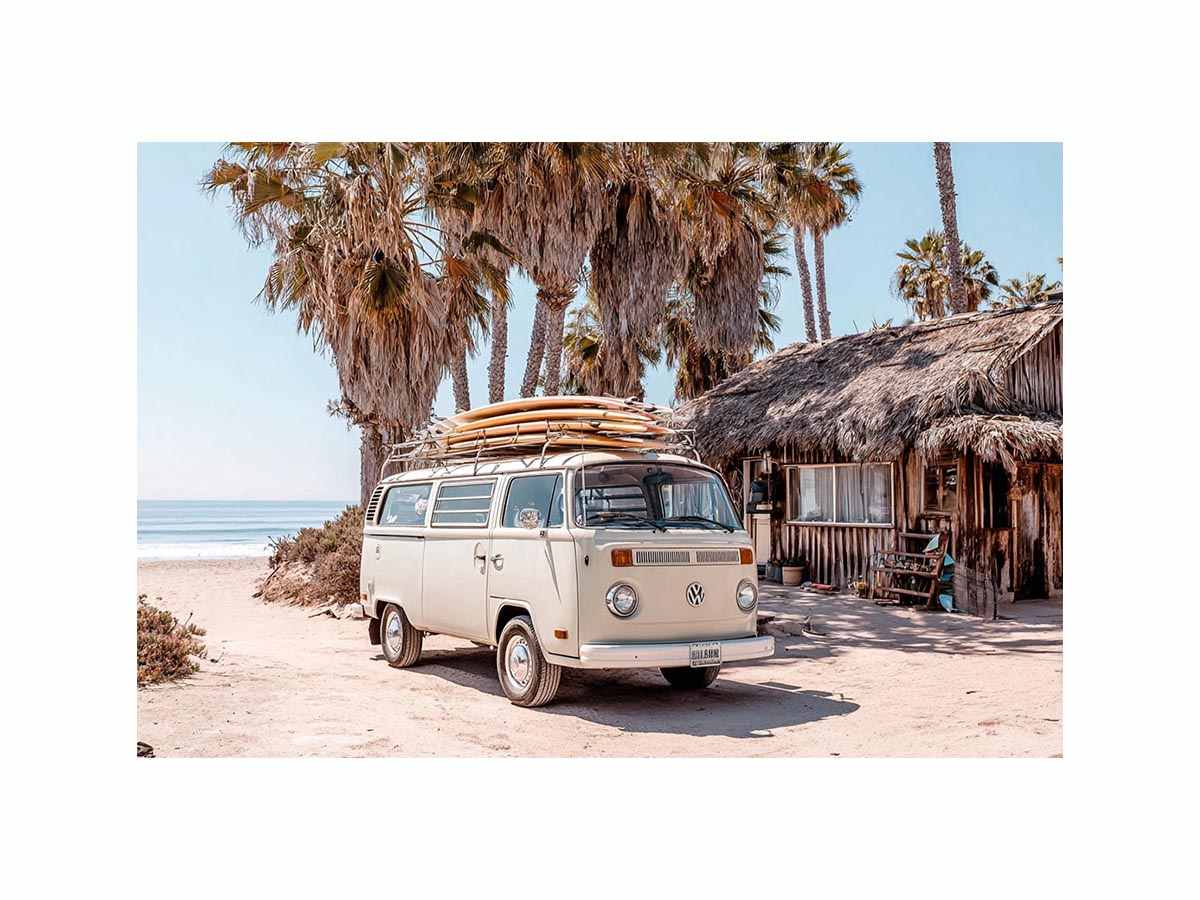 Cream vintage surf van near a palm beach hut for rustic coastal living room decor.
