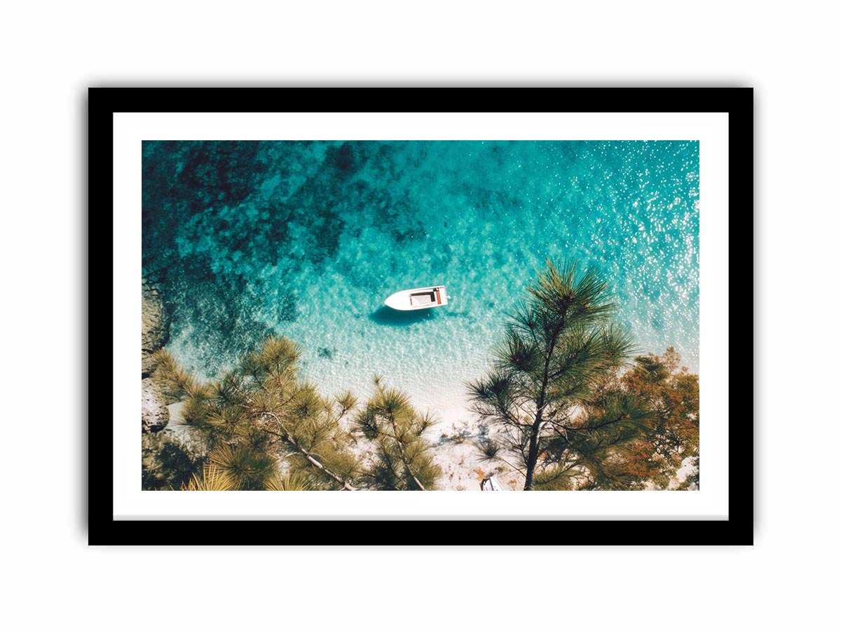 Aerial turquoise cove with white boat and pine trees for calming coastal wall art.