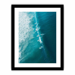 Aerial coastal photography of surfers on turquoise ocean waves for modern beach house decor.