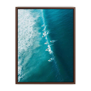 Aerial coastal photography of surfers on turquoise ocean waves for modern beach house decor.