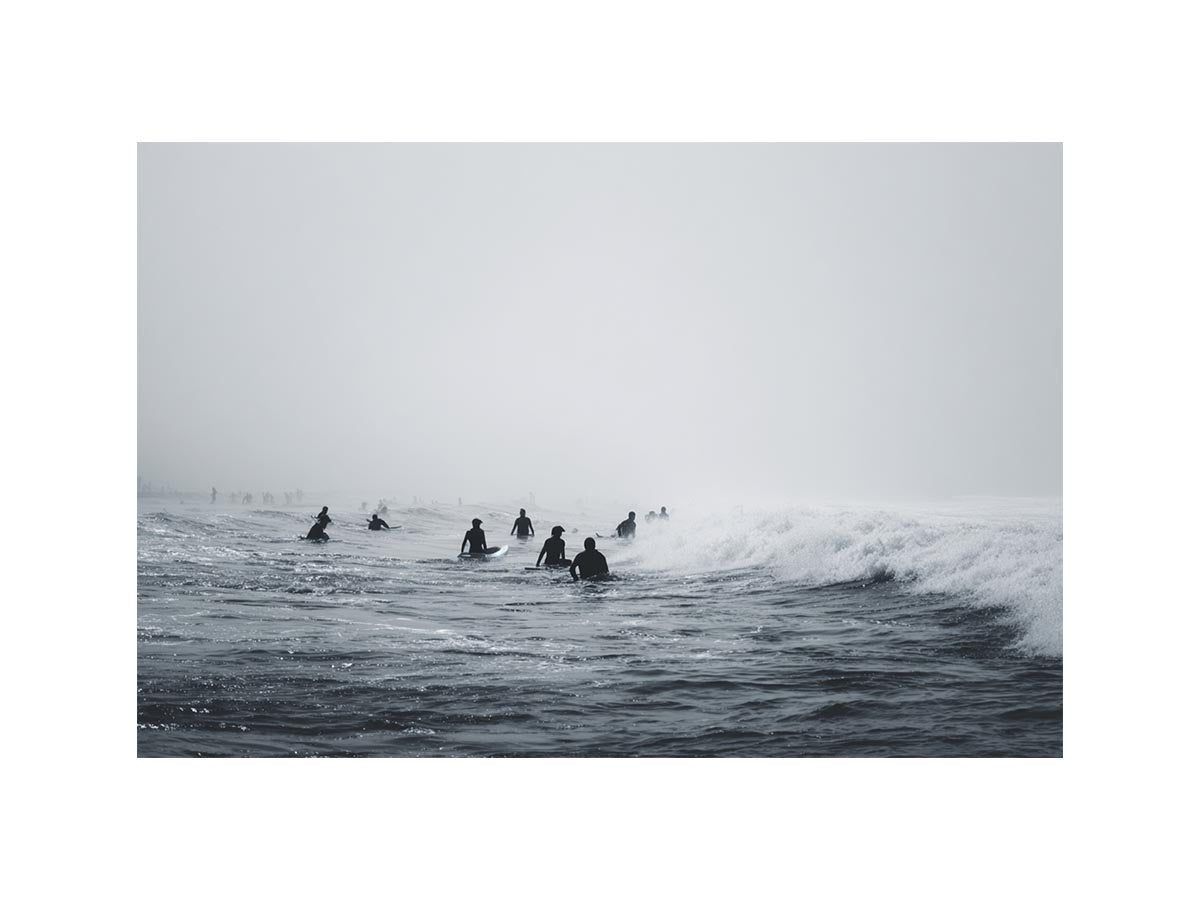 Moody surf canvas art with surfers and misty ocean waves for modern office decor.