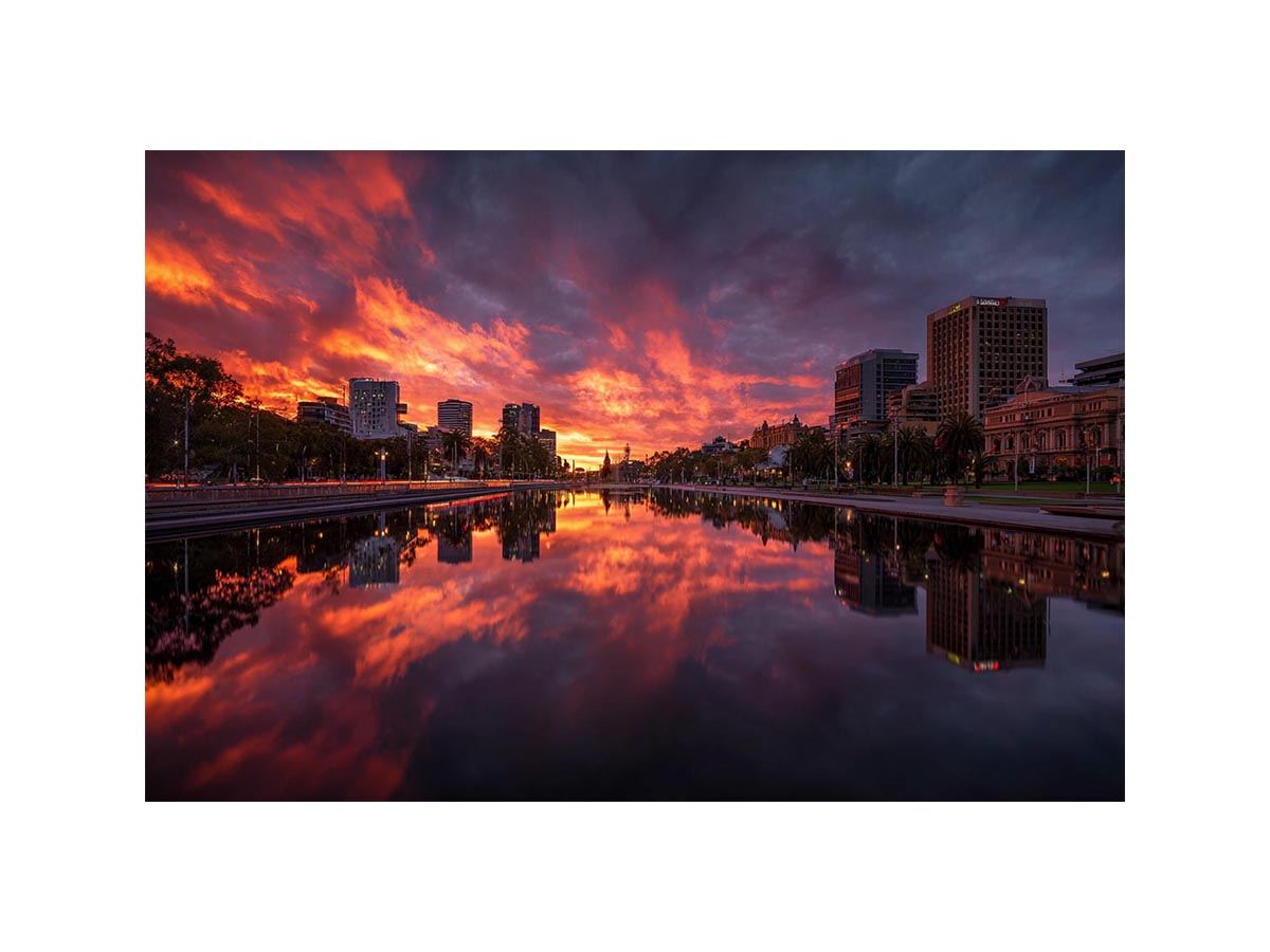 Dramatic city skyline canvas art with fiery sunset reflections for modern decor.