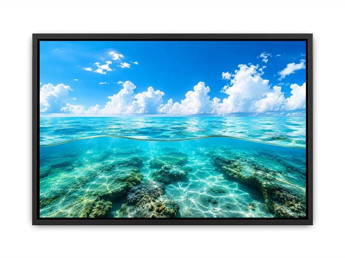Bright split-view ocean wall art featuring crystal-clear turquoise water, underwater rock formations, and soft clouds beneath a vivid blue sky.