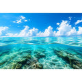 Bright split-view ocean wall art featuring crystal-clear turquoise water, underwater rock formations, and soft clouds beneath a vivid blue sky.