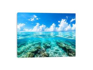 Bright split-view ocean wall art featuring crystal-clear turquoise water, underwater rock formations, and soft clouds beneath a vivid blue sky.