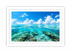 Bright split-view ocean wall art featuring crystal-clear turquoise water, underwater rock formations, and soft clouds beneath a vivid blue sky.