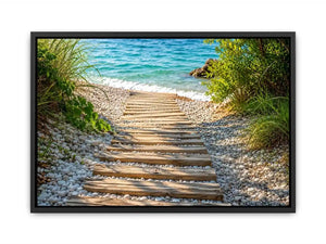 Rustic wooden pathway leading across a pebble beach toward turquoise ocean waves