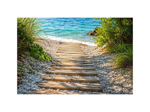Rustic wooden pathway leading across a pebble beach toward turquoise ocean waves