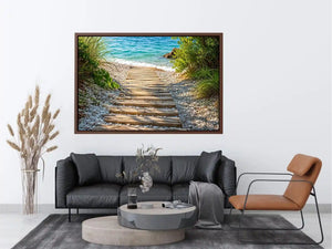 Rustic wooden pathway leading across a pebble beach toward turquoise ocean waves