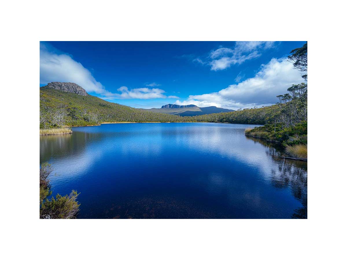Serene mountain lake landscape with blue water and sky for modern living room wall art.