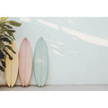 Pastel surfboards by a white wall for calm coastal bedroom decor.