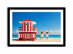 Minimal coastal beach scene with red lifeguard hut blue ocean and two women walking aesthetic wall art
