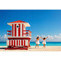 Minimal coastal beach scene with red lifeguard hut blue ocean and two women walking aesthetic wall art
