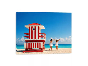 Minimal coastal beach scene with red lifeguard hut blue ocean and two women walking aesthetic wall art