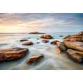 Serene coastal landscape wall art featuring smooth ocean waves, natural shoreline rocks, pastel sunrise sky, and luxury long exposure beach photography for modern coastal interiors