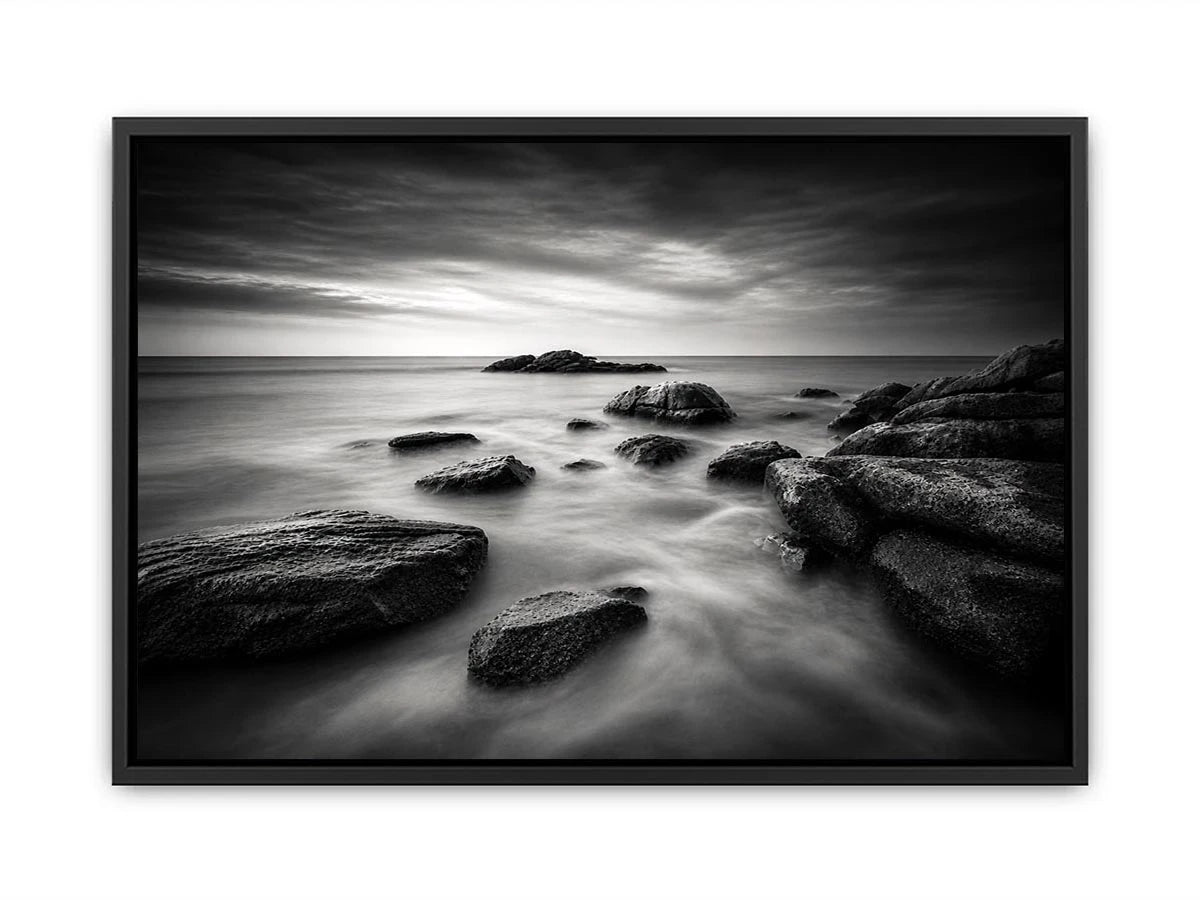 Black and white ocean wall art with dramatic coastal rocks, misty waves, and moody storm clouds in contemporary monochrome seascape style