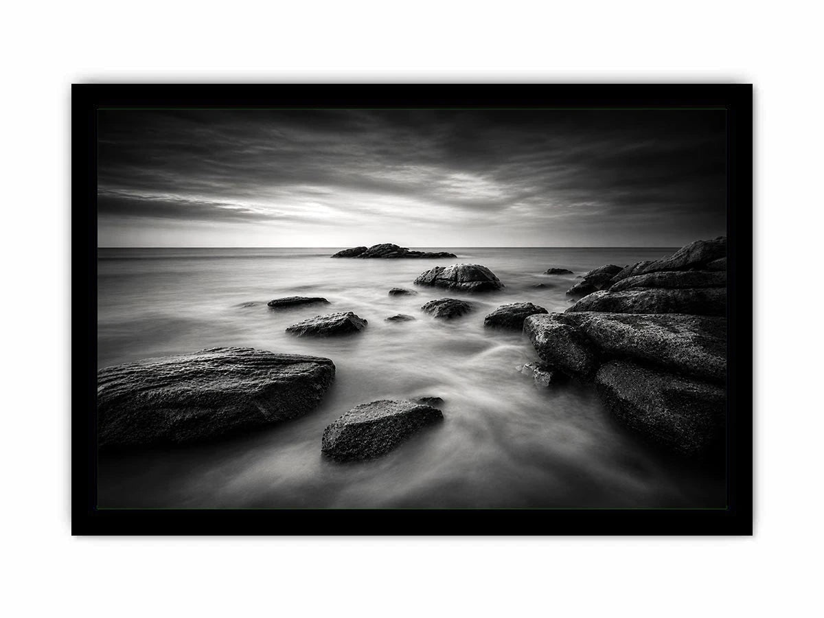 Black and white ocean wall art with dramatic coastal rocks, misty waves, and moody storm clouds in contemporary monochrome seascape style
