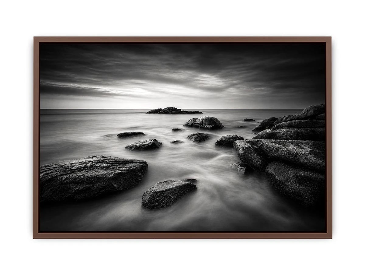 Black and white ocean wall art with dramatic coastal rocks, misty waves, and moody storm clouds in contemporary monochrome seascape style