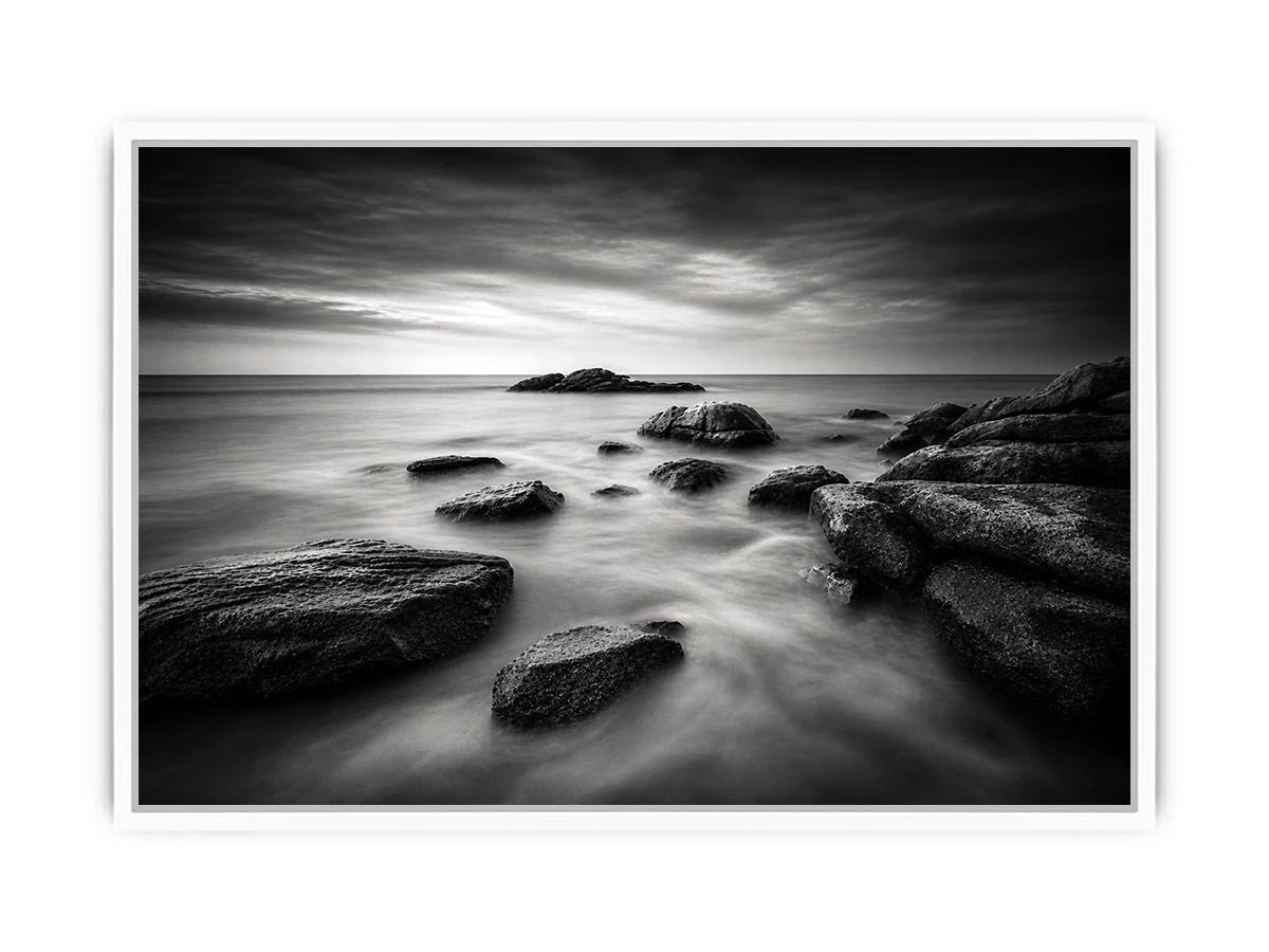 Black and white ocean wall art with dramatic coastal rocks, misty waves, and moody storm clouds in contemporary monochrome seascape style