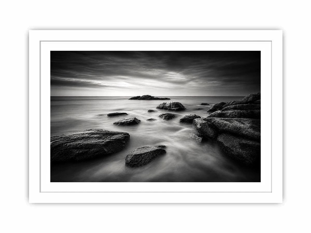 Black and white ocean wall art with dramatic coastal rocks, misty waves, and moody storm clouds in contemporary monochrome seascape style