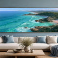 Panoramic coastal canvas art with turquoise ocean, rocky headlands, and beach scenery for modern living room decor.