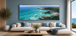 Panoramic coastal canvas art with turquoise ocean, rocky headlands, and beach scenery for modern living room decor.