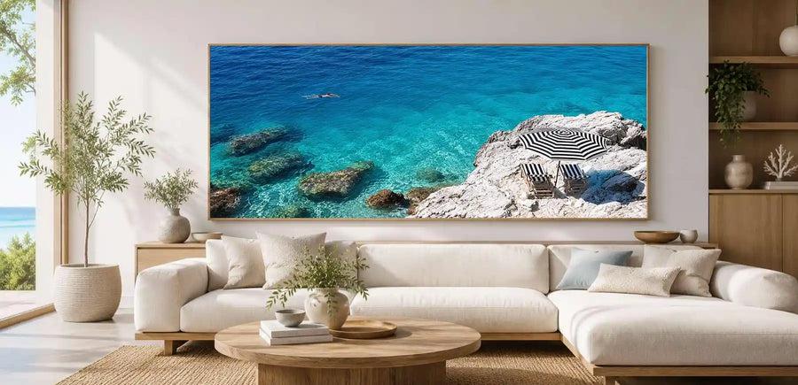 Turquoise coastal cove canvas art with white rocks, striped umbrella and clear sea.