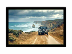 Off-road vehicle on a coastal dirt track overlooking turquoise waves, limestone sea stacks and golden cliffs beneath a cloudy sky