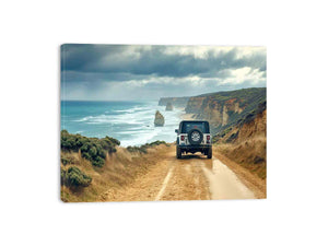 Off-road vehicle on a coastal dirt track overlooking turquoise waves, limestone sea stacks and golden cliffs beneath a cloudy sky